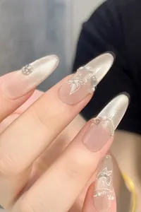 Detail of almond cat eye press-on nails with hand-painted flowers, pearls and rhinestones