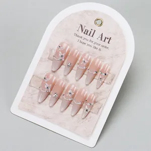 Pink cat-eye press-on nails with butterfly charms, pearls, and crystals in long almond shape