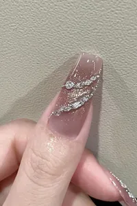 Macro detail of gradient pink press-on nails with sparkling rhinestones and silver accents