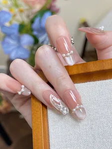Détail macro de faux ongles rose nu avec accents de perles et finition œil de chat