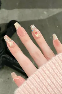 Detail of pink and gold cat-eye press-on nails with rhinestones and pearl accents