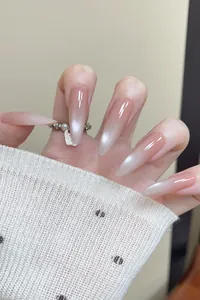 Detail of long almond nails featuring nude pink gradient and cat eye pearl finish