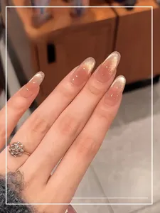 Detail view of pink gradient press-on nails with golden cat-eye glitter and silver beads