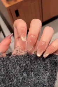 Detail of almond pink gradient press-on nails with golden glitter tips and jelly texture
