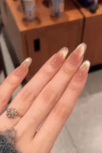 Macro view of long almond-shaped press-on nails with champagne gold cat-eye gradient