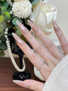 Close-up of pink cat-eye stiletto press-on nails with glitter and metallic ring detail