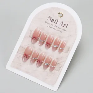 Elegant nude cat-eye press-on nails with red bow and pearl chain details