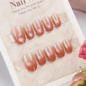 Macro shot of 10 pieces of glossy ombre pink to brick red press-on nail tips on card