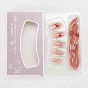 Detail of nude pink cat-eye press-on nails with red bow and pearl embellishments