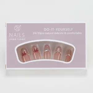 Nude cat-eye press-on nails with red bows, pearls, and rhinestones in a display box
