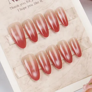 Detail of almond-shaped cat-eye press-on nails with deep red gradient and shimmer