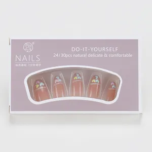 Vue détaillée des faux ongles dégradés roses avec charms cœurs dans leur boîte