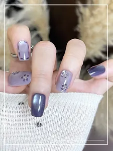 Detail of purple cat eye press-on nails with 3D floral rhinestones on soft fabric