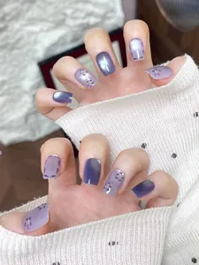 Detail of handmade purple cat-eye press-on nails with 3D flower and rhinestone decor