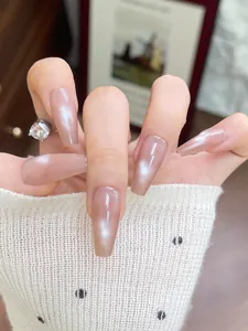 Close-up of long coffin-shaped nude cat-eye press-on nails with shiny pearlescent finish