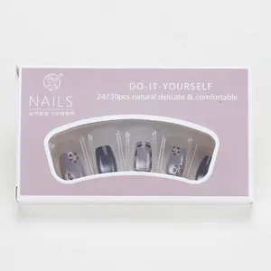 Detail of press-on nails set in cat-eye finish with floral rhinestones and purple box
