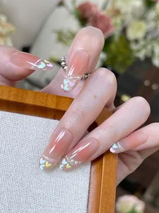 Detail of pink ombre press-on nails with colorful heart sequins and tiny pearls