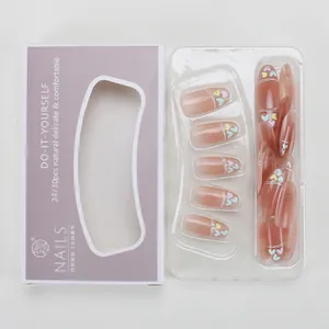 Flat lay of nude press-on nails with heart patterns and packaging box