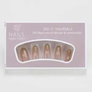 Detalle de uñas postizas degradadas marrón nude con brillo cat eye en caja rosa