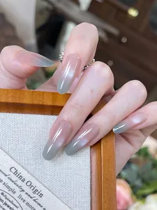 Makroaufnahme langer Mandel-Nägel zum Aufkleben mit rosa-grauem Farbverlauf und Cat-Eye-Effekt