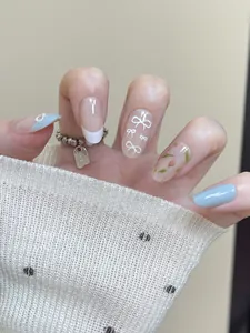 Detail of light blue press-on nails with white bow designs and tulip floral patterns