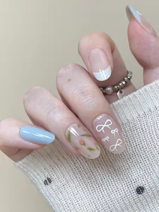 Detail of French press-on nails with floral designs and white hand-drawn bows