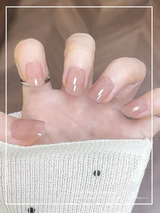 Close-up of translucent nude pink press-on nails with a high-gloss finish on a hand