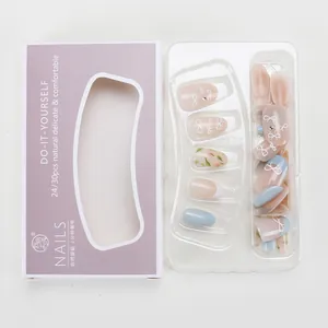 Detail of nude and blue press-on nails with bow designs and French tips in packaging