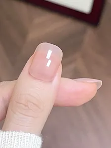 Close-up of translucent nude pink press-on nails in a short square shape