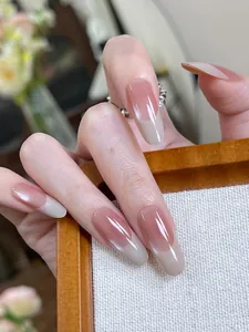 Macro view of almond shape French gradient press-on nails with glossy nude pink finish