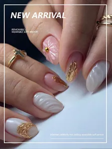 Close-up of pink press-on nails with 3D floral accents and gold foil on a woman's hand