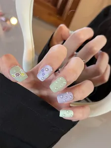 Detalle macro de uñas cortas cuadradas mate con patrones florales y perlas 3D