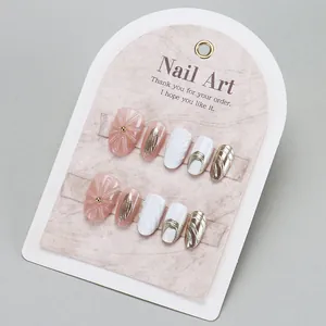 Pink and white press-on nails set with 3D flower embossing and gold texture accents