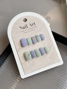 Detalle de uñas postizas cortas cuadradas con gotas de agua 3D y patrones florales