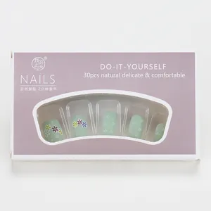 Detalle de uñas postizas verde menta con diseños florales y gotas decorativas en 3D