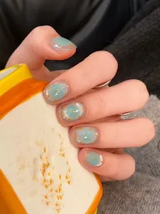 Gros plan d'ongles bleus courts à pois orange sur une main tenant une tasse colorée
