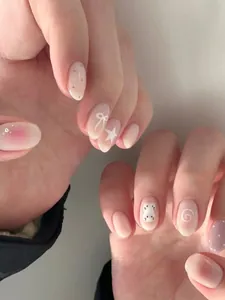 Detalle de uñas postizas hechas a mano con dibujos animados y perlas decorativas