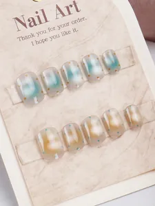 Gros plan d'ongles press-on cat-eye avec dégradé vert et doré et motifs à pois