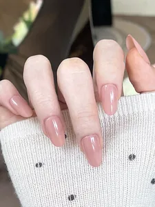 Close-up of nude pink oval press-on nails with a glossy mirror finish on a hand