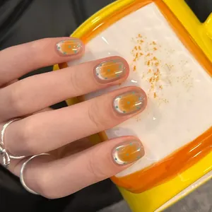 Faux ongles Cat-eye français avec dégradé orange et pois bleus sur la main