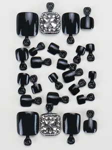 Flat lay macro of black press-on toe nails with rhinestones showing various sizes and details