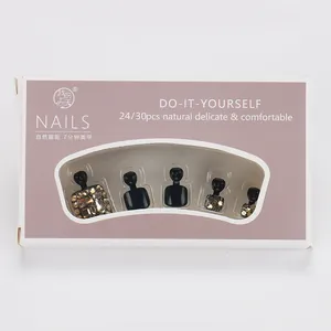 Détail de faux ongles de pieds noirs de luxe avec strass dorés étincelants en coffret