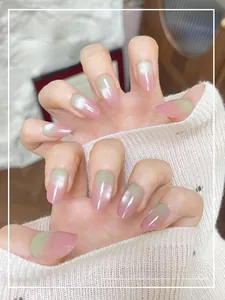 Detail of pink and green gradient cat-eye press-on nails on model hands with glossy finish