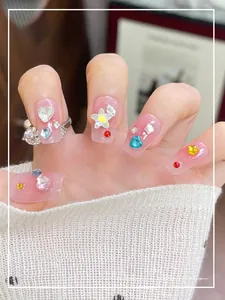 Close-up of pink gradient wearable nails with 3D heart and star rhinestones on model hand