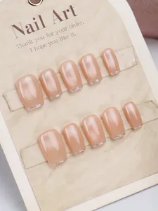 Macro detail of cat-eye press-on nails with silver glitter tips on a beige display card