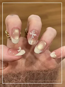 Détail de faux ongles œil-de-chat blanc nacré avec nœuds 3D et accents dorés