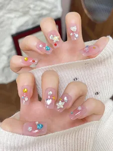 Detail of pink press-on nails with 3D stars, colorful rhinestones and pearls