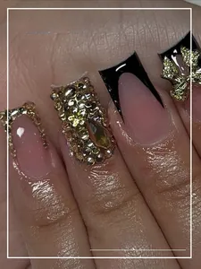 Detail of square black French nails with gold glitter and rhinestones on fingers