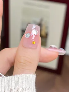 Close-up of pink translucent press-on nails with silver hearts and star charms