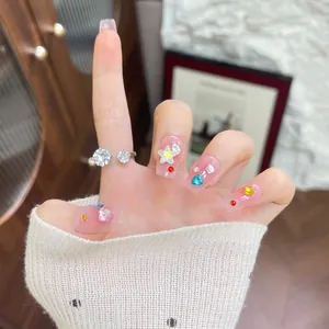 Close-up of pink gradient press-on nails with 3D stars and sparkling zircon ring